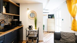A modern kitchen with a coffee machine, a round mirror, and a dining area with a table and chairs. - Marghareta Apartment NO 1 - TOP Location (Dubrovnik)