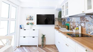 A modern kitchen with white cabinets, a wooden countertop, a flat-screen TV, and a tiled backsplash. - Marghareta Nest 2 - TOP Location (Dubrovnik)