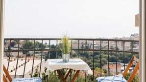 Varanda com mesa e cadeiras, um vaso de planta e vista para a cidade.