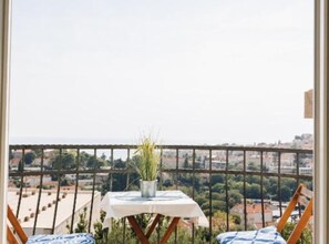 A balcony with a table and chairs, a potted plant, and a view of a cityscape. - Apartment Marghareta (Dubrovnik)