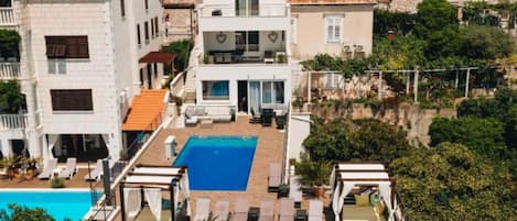 Un edificio residencial con piscina en la azotea, varios balcones y fachada de piedra.