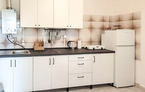 A kitchen with white cabinets, a black countertop, a kettle, a coffee maker, and a refrigerator. - 1 bedroom amazing home in Pupnat (Pupnat)