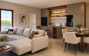 Ein modernes Wohnzimmer mit einer Couch, einem Essbereich mit Stühlen, einer Küche mit Einbauofen und einem großen Fenster.