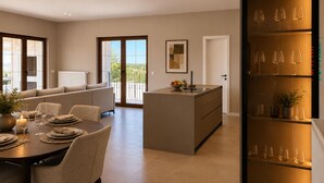 Una cocina moderna con una isla central, comedor con una mesa redonda y un botellero.