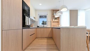 Eine moderne Küche mit Holzausstattung, einem eingebauten Ofen und Pendelleuchten.