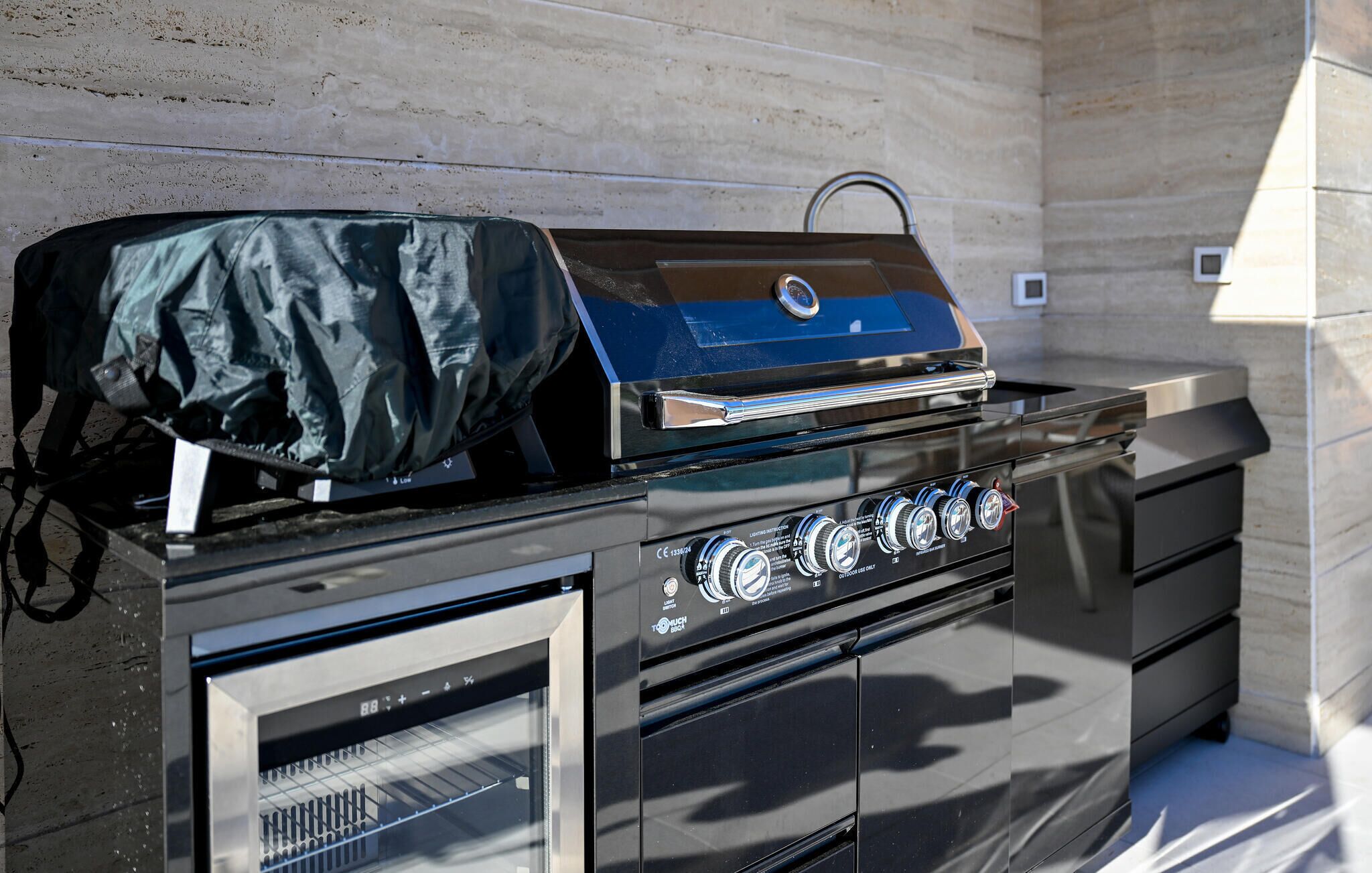 A black outdoor grill with a blue lid, control knobs, and a vented cabinet below.
