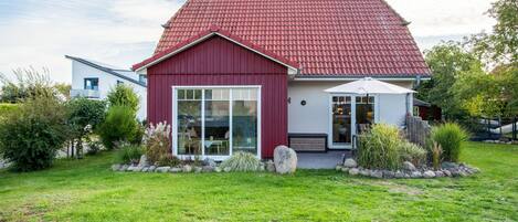 A modern house with a red roof, large windows, and a well-maintained garden.