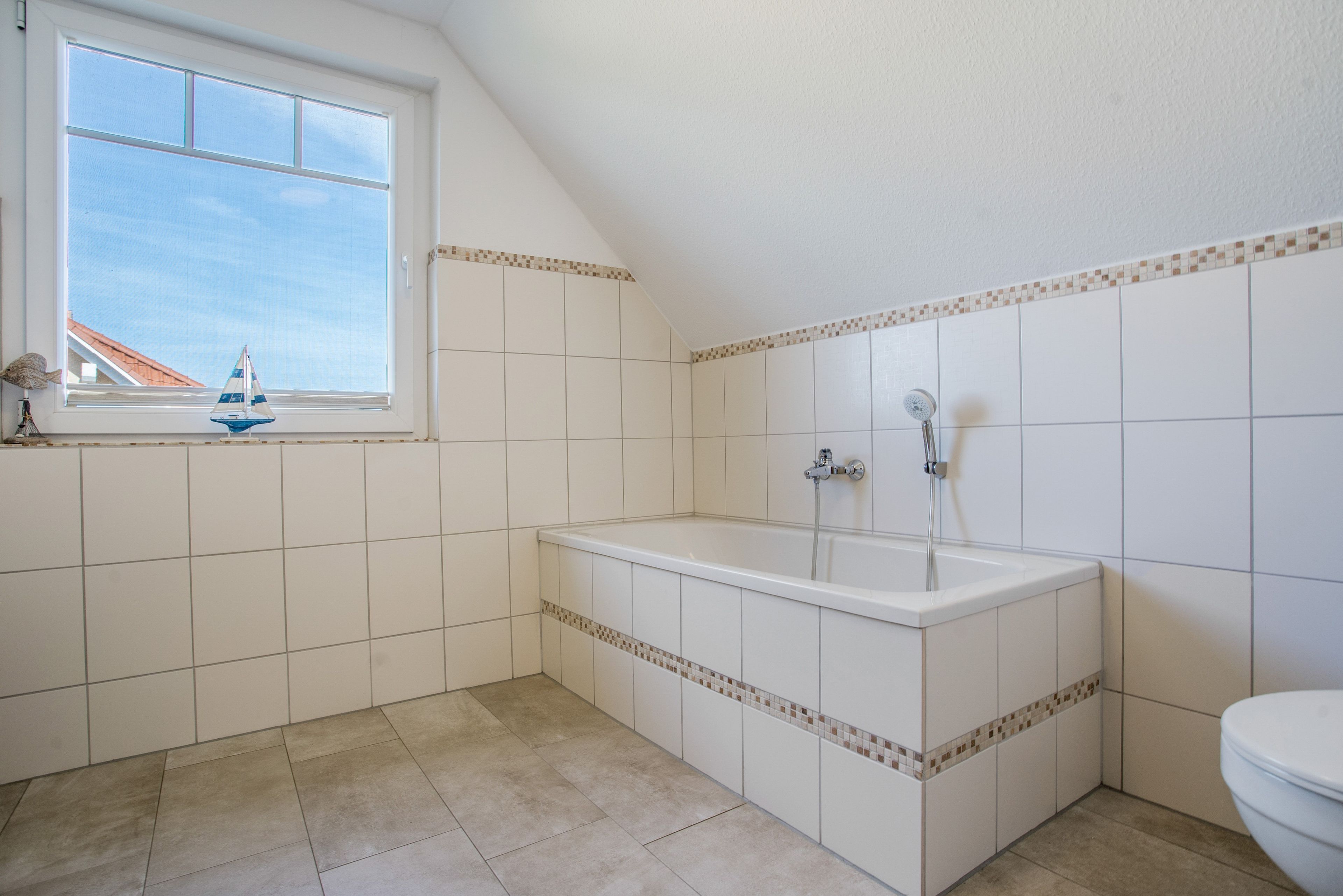 Ein Badezimmer mit einer Badewanne, einem Fenster und Fliesenwänden.