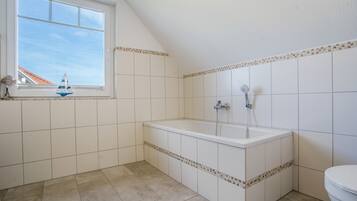 Ein Badezimmer mit einer Badewanne, einem Fenster und Fliesenwänden.