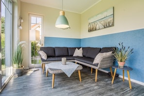 A modern living room with a sectional sofa, a coffee table, and a potted plant.