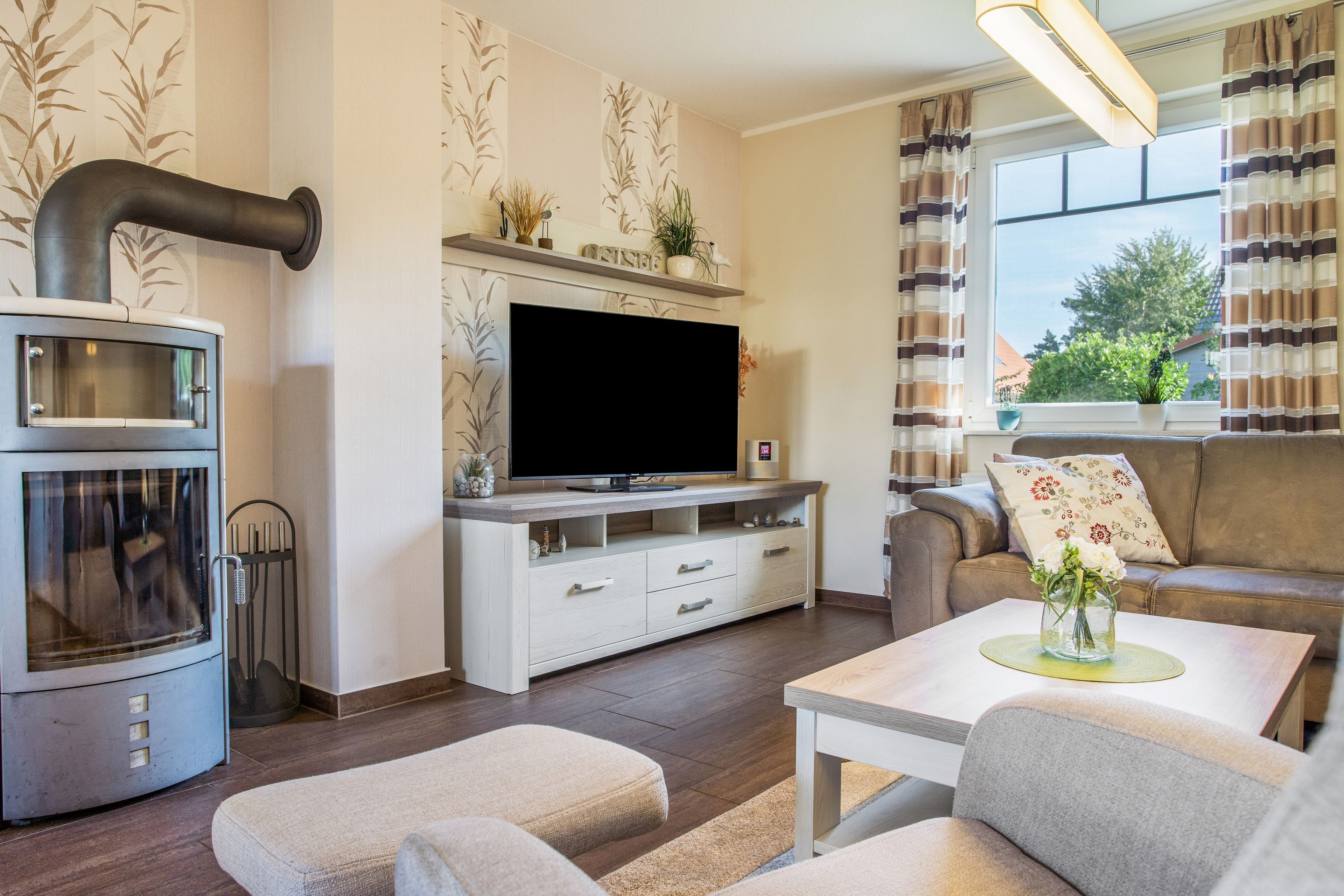 Ein modernes Wohnzimmer mit Kamin, Fernseher, Sofa und Essbereich.