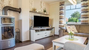 Ein modernes Wohnzimmer mit Kamin, Fernseher, Sofa und Essbereich.