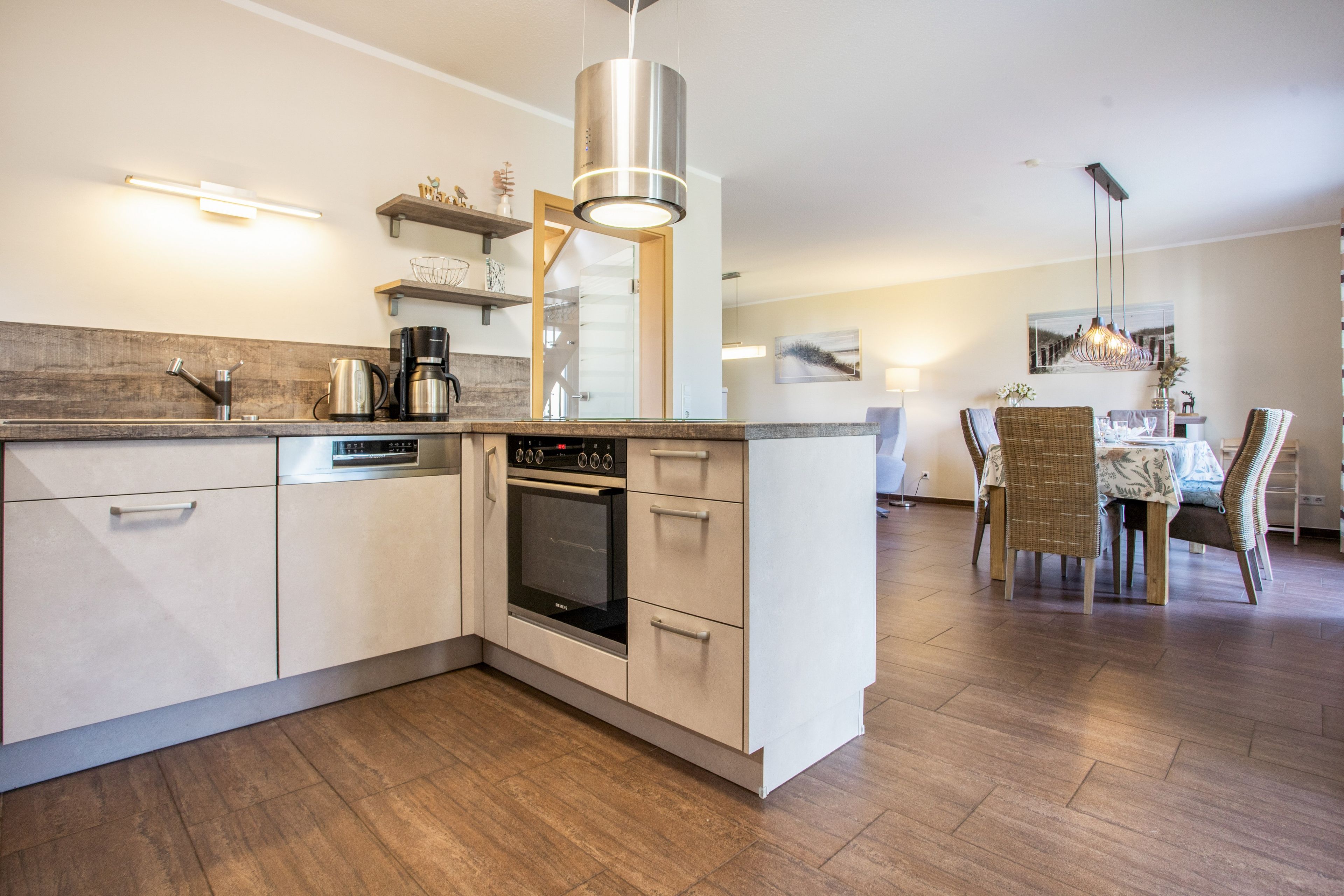 A modern kitchen with a built-in oven, a coffee maker, and a stainless steel range hood.
