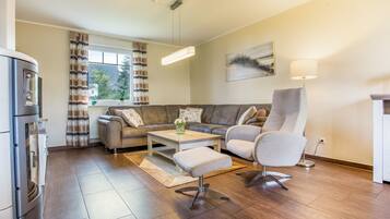 A modern living room with a sofa, armchair, coffee table, and a dining table.