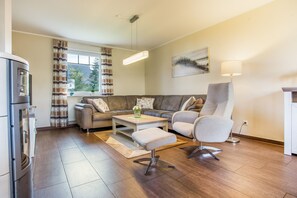 A modern living room with a sofa, armchair, coffee table, and a dining table.