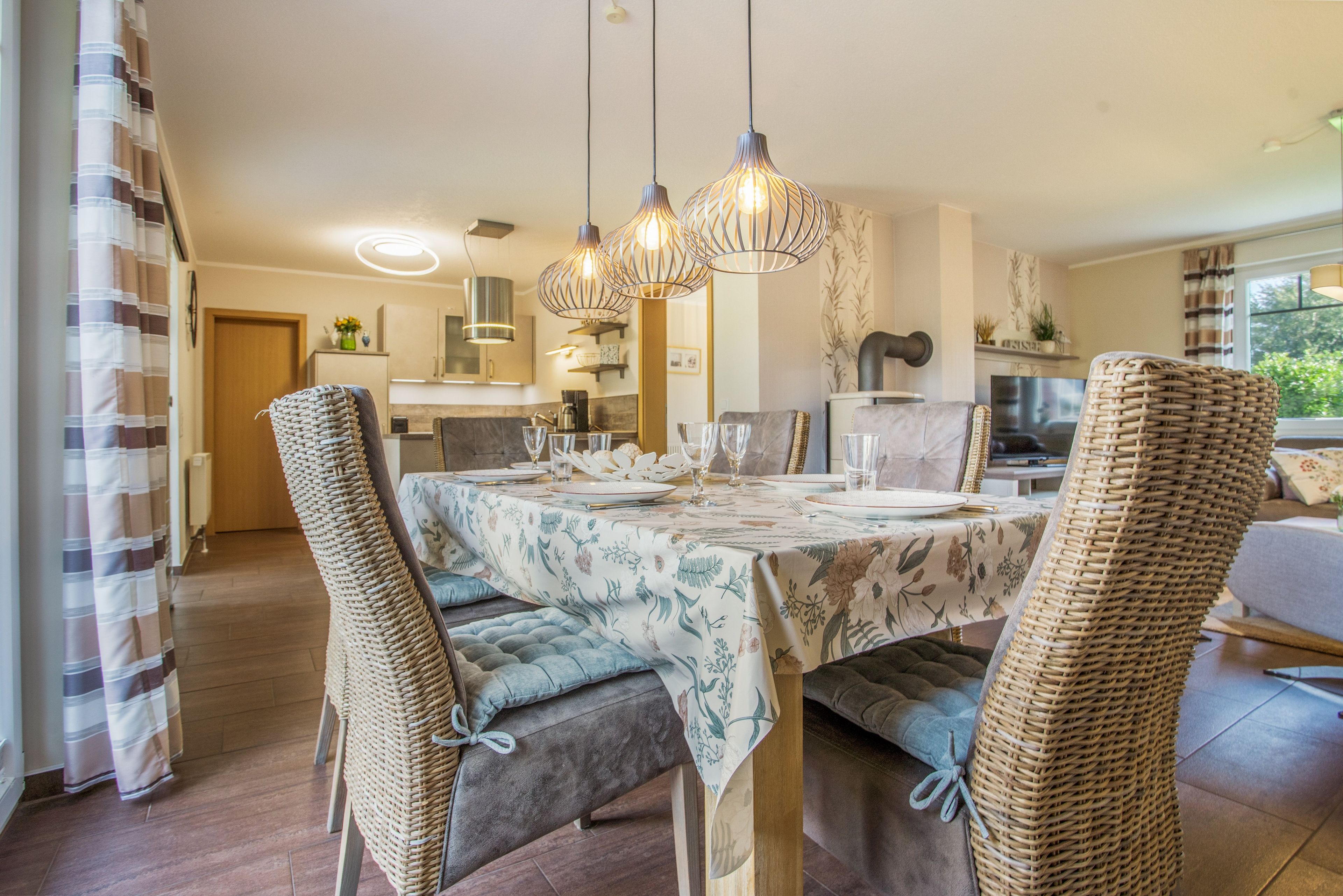 A dining area with a table set for four, surrounded by wicker chairs.