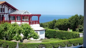 Ein zweistöckiges Haus mit einem roten Balkon, einer weißen Fassade und Blick aufs Meer.