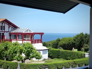 Ein zweistöckiges Haus mit einem roten Balkon, einer weißen Fassade und Blick aufs Meer.