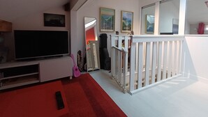 Ein Wohnzimmer mit Fernseher, rotem Teppich, weißer Geländer und gerahmten Bildern an der Wand.