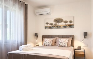 Ein Hotelzimmer mit einem Bett, einer Klimaanlage, einem Gemälde und zwei Wandleuchten.