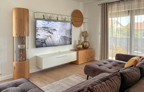 Ein modernes Wohnzimmer mit einem großen Flachbildfernseher, Holzmöbeln und einer Vitrine.