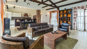 Een ruime woonkamer met een donker leren bank, een houten salontafel en een inbouwkast met boeken.
