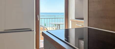 Una cocina con vista al mar a través de un ventanal abierto.