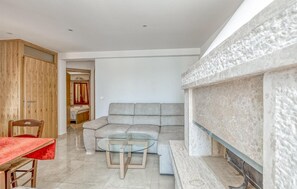 Ein Wohnzimmer mit einer Couch, einem Glastisch, einem Holzessttisch und einem Kamin.