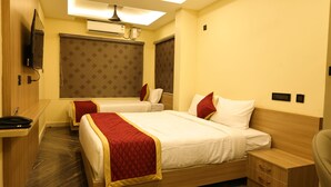 Quarto de hotel com duas camas, televisão, ar condicionado e escrivaninha com cadeira.