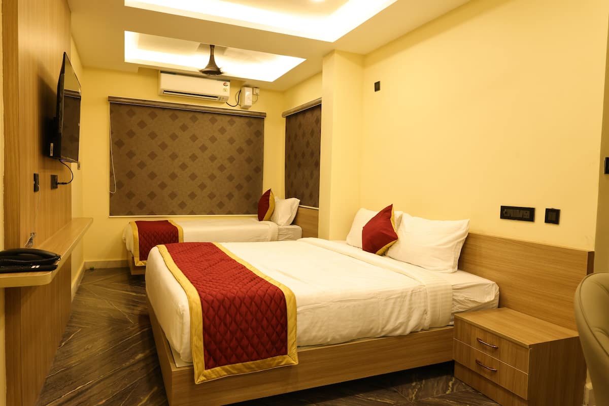 A hotel room with two beds, a TV, an air conditioning unit, and a desk with a chair.
