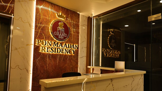 Um balcão de recepção com bancada de mármore e placa indicando 'PON MAADAN RESIDENCY' hotel.