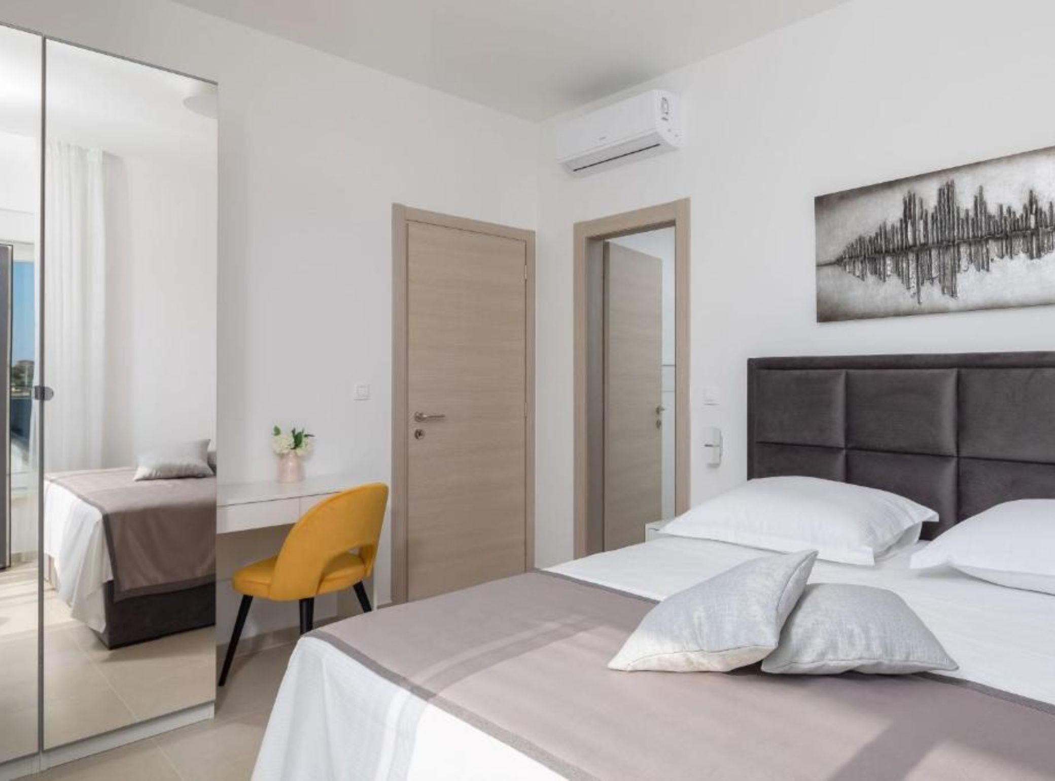 Une chambre d’hôtel avec un lit, un bureau, une chaise, un miroir et un tableau au mur.