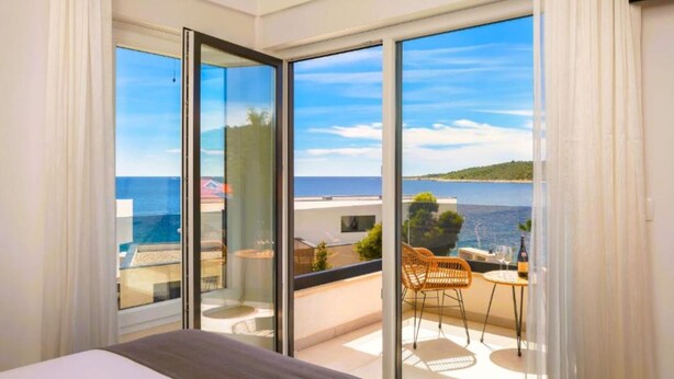 Un dormitorio con un amplio ventanal corredera que da a un balcón con vistas al mar.