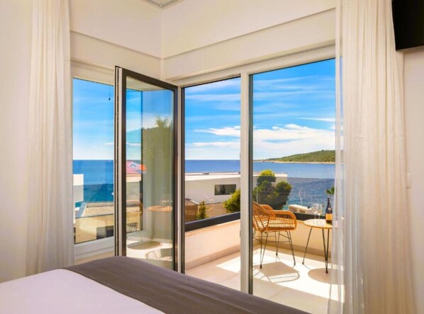 Ein Schlafzimmer mit einer großen Schiebeglasdoor zum Balkon mit Meerblick.