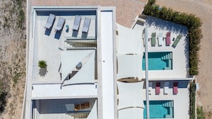 An aerial view of a modern hotel with a rooftop pool, sun loungers, and a clear view of the surrounding landscape. - Villa Nexia (Sibenik)