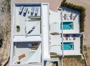 Ein Luftbild eines modernen Hotels mit Pool auf dem Dach, Liegestühlen und freiem Blick auf die umliegende Landschaft.