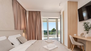 Ein modernes Hotelzimmer mit einem großen Bett, einem Schreibtisch, einem Stuhl und einem Fernseher.