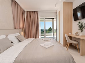 Ein modernes Hotelzimmer mit einem großen Bett, einem Schreibtisch, einem Stuhl und einem Fernseher.