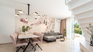 Ein modernes Wohnzimmer mit Essbereich, einer Couch, einem Couchtisch und einer Wand mit floralem Wandbild.