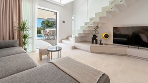 Ein modernes Wohnzimmer mit einer Couch, einem Couchtisch, einem Fernseher und einer Treppe.