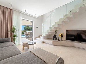 Ein modernes Wohnzimmer mit einer Couch, einem Couchtisch, einem Fernseher und einer Treppe.