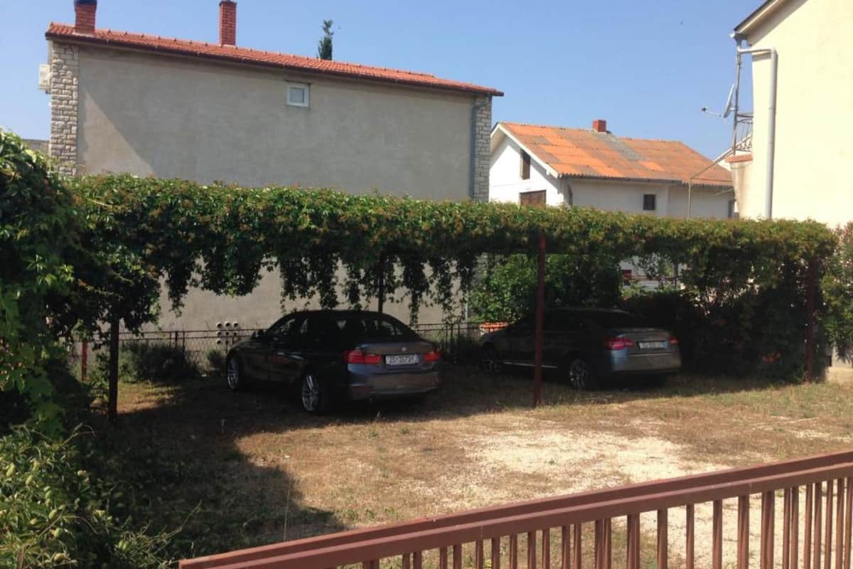 Un barrio residencial con una casa, un coche y una valla.