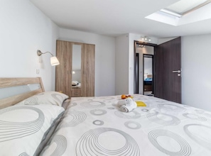 Ein Schlafzimmer mit Bett, Kleiderschrank, Spiegel und einem Oberlicht.