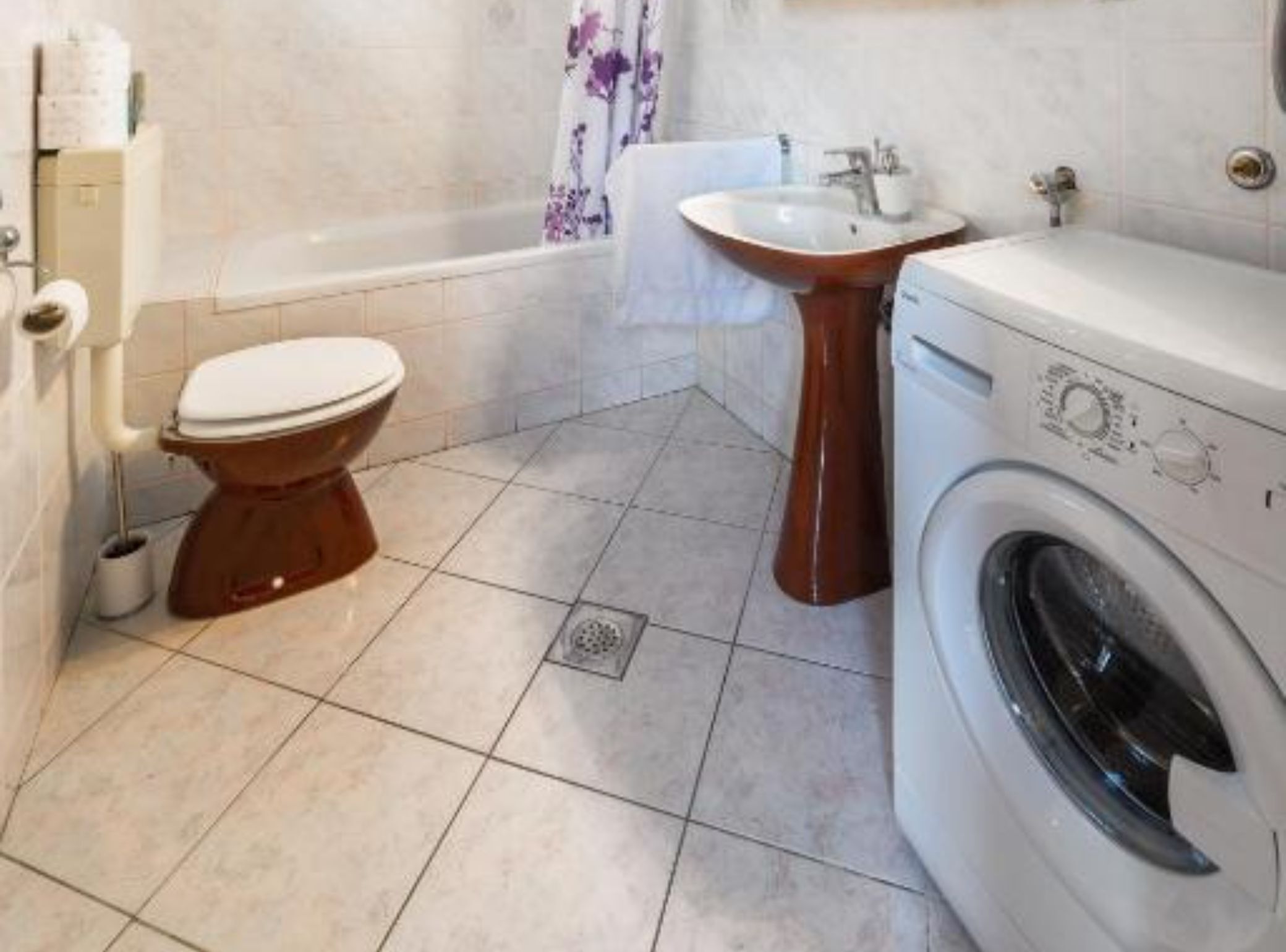 Ein Badezimmer mit Toilette, Waschbecken und Waschmaschine.