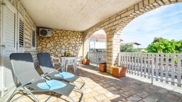 A covered outdoor area with stone walls, a white fence, and two lounge chairs.