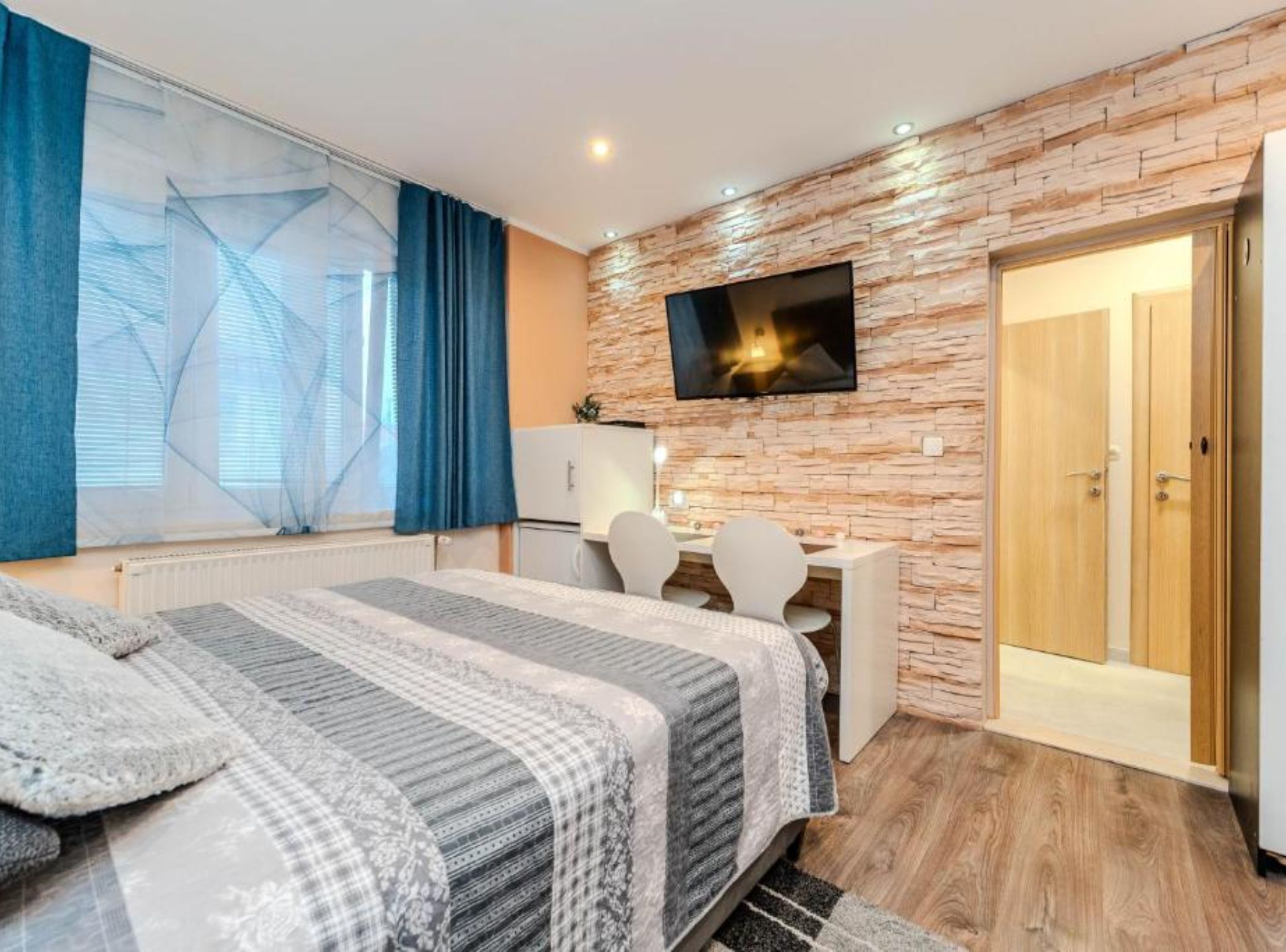 Un dormitorio moderno con cama, escritorio, televisor y armario.