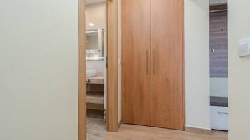 Un pasillo con un armario de madera, un baño con lavamanos blanco e interruptor de luz en la pared.