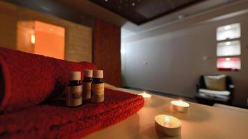 A spa room with a red towel, candles, and essential oil bottles.