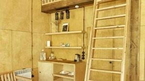 Una habitación con cama tipo altillo, muebles de madera y una escalera.