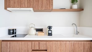Eine moderne Küche mit Holzschränken, einer weißen Arbeitsplatte, einem Wasserkocher, einer Kaffeemaschine und einem Spülbecken.